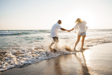 Wall Mural - Young beautiful couple walking on beach near sea