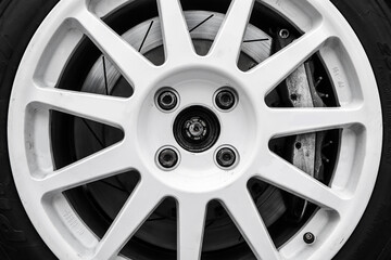 Wall Mural - The detail of a wheel of a rallye car with part of the rim, brake caliper and brake disc visible. Black and white edit.  