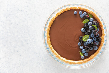 Dark chocolate mousse tart decorated with fresh blueberries and the mint, view from above