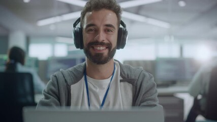 Fototapete - Office: Portrait of Happy IT Programmer Wearing Headphones Working on Desktop Computer, Looking at Camera and Smiling. Male Software Engineer Developing App, Video Game. Listening to Podcast, Music
