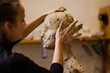 Young woman sculpts from clay a head with her hands

