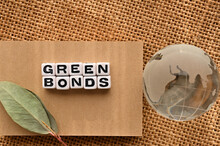There Is A Word Cube Lined Up With The Word GREEN BONDS. A Glass Earth Is Placed Next To It.