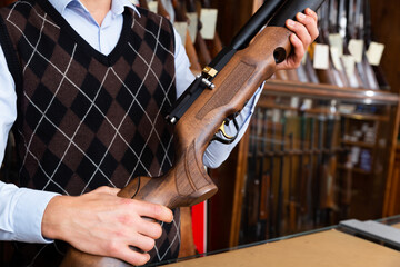 Closeup of modern sporting air PCP pump-action rifle in hands of gun shop seller.