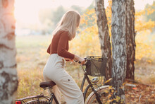Happy Active Young Woman Riding Vintage Bicycle In Autumn Park At Sunset.
