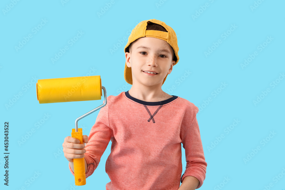 Little boy with paint roller on color background