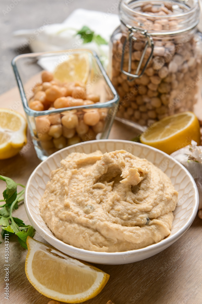Bowl with tasty hummus and ingredients on table