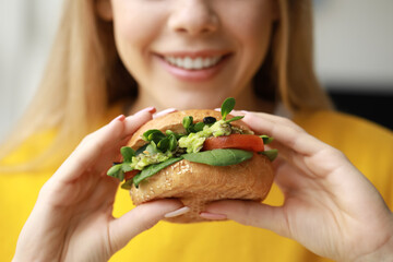 Sticker - Young woman with tasty vegan burger at home, closeup