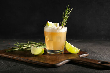 Glass of tasty whiskey sour cocktail on dark background