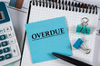 OVERDUE - word on a blue notebook on the background of a notebook, calculator and pen