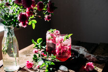 Cold Cocktail Of Rose Petals With Ice On A Wooden Table. Rose Drink
