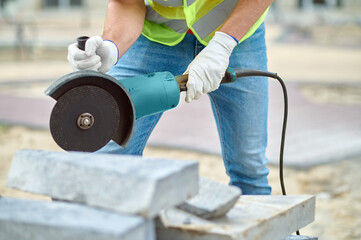 Poster - Experienced adult Caucasian male builder cutting cement tiles outdoors