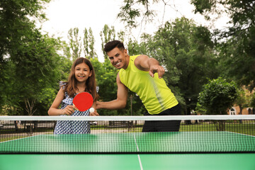 Wall Mural - Happy man with his daughter playing ping pong in park