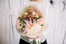 Very Nice Young Woman Holding Big And Beautiful Bouquet Of Fresh Gerbera Daisy, Roses, Lupines, Dahlia, Statice, Chrysanthemum Flowers In Pastel Cream Colors, Cropped Photo, Bouquet Close Up