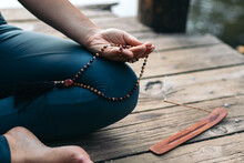 Crop Woman With Prayer Beads Meditating On Pier
