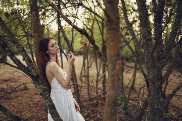 Wall Mural - Woman in white dress leaning on a tree forest walk leisure