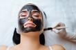 © руслан малыш - cosmetologist applying black mask on pretty woman face wearing black gloves, gorgeous woman in spa having facial procedures