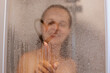 © sementsova321 - Portrait of beautiful woman taking a shower and drawing heart on the sweat and blurred glass, blur shot of happy smiling woman with wet hair, morning procedures.