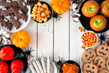 Canvas Print - Classic Halloween treat frame over a white wood background with copy space. Overhead view. Selection of candied apples, cookies, candy and sweets.