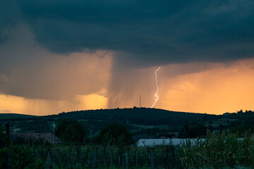 Wall Mural - lightning against orange sky during sunset