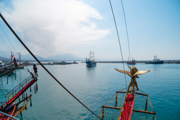 Wall Mural - Old pirate ship on the water of Mediteranean sea. Tourist entertainment, coastal tour. Summer sunny day. Mountain shore of Alanya bay. Turkey.