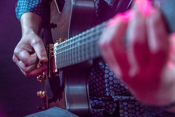 Sticker - Closeup view of a man wearing a shirt playing a guitar on stage at the concert