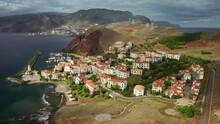 Madeira Islands, Portugal. Aerial View Of Charming Low-rise Cottages At The Edge Of The Shoreline. Lush Archipelago Washed With Atlantic Waters. High Quality 4k Footage