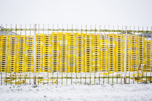 Yellow Pallets Piled On Top Of Each Other Behind A Fence.