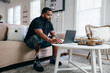 © Creative Flame - Black man with prosthetic leg working from home on laptop