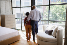 Rear View Of Father And Son Standing In Front Of Window In Living Room