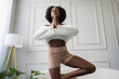 © Creative Flame - Young woman doing eka pada pranamasana yoga pose in living room