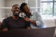 © Creative Flame - Black Couple sitting on sofa and laughing
