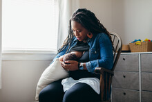Black Woman Breastfeeding Child At Home