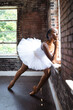 © Creative Flame - Black ballerina doing powerful ballet dance pose, wearing pointe shoes and white tutu