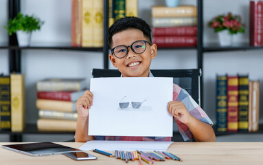 Smart young Asian boy wearing glasses showing the art work, sunglasses hand drawing with pride and smile face