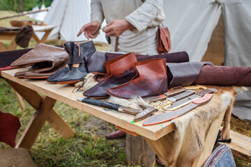 Craft shoemaker demonstrates the process and the products of his work on the festival workshop, tools and leather at cobbler workplace, diy, master of artisanal thing, middle age re-enactment