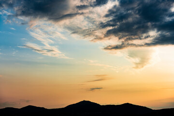 Wall Mural - Stunning view of a dramatic sunset with some clouds over the silhouette of a mountain range. Romantic sky, natural background, Sardinia, Italy.