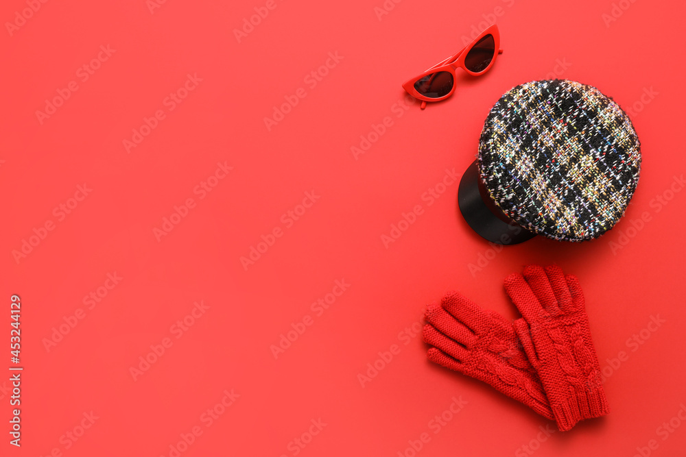 Stylish cap, gloves and sunglasses on color background