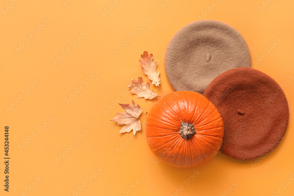 Composition with stylish berets and pumpkin on color background