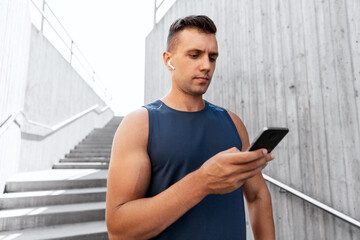 Poster - fitness, sport and technology concept - young athlete man with earphones and smartphone listening to music outdoors