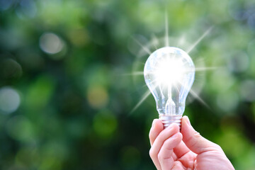 Poster - Hand holding Glowing light bulb in idea, innovation and inspiration concept