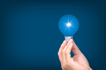 Poster - Hand holding Glowing light bulb in idea, innovation and inspiration concept, illuminated light bulb on blue bakground