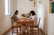 © ADDICTIVE STOCK - Happy lesbian couple playing cards at table at home