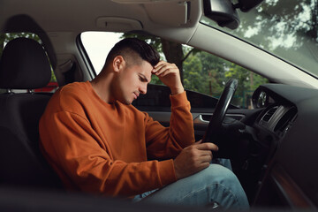 Stressed man in driver's seat of modern car