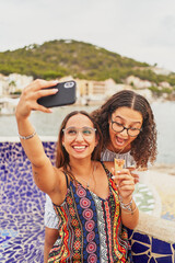 Wall Mural - Two young spanish cheerful women taking selfies eating ice cream