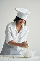 Wall Mural - woman in chef's uniform working with dough flour products cooking