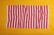 Crumpled striped beach towel on yellow background, top view