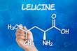 Hand with pen drawing the chemical formula of leucine