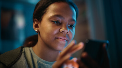 Portrait of a Teenage Multiethnic Black Girl Using a Smartphone. Young Female Browses Internet, Checks Social Media, Chats with Friends.