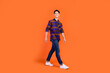 © deagreez - Photo of pretty sweet teenager man dressed checkered clothes walking smiling isolated orange color background