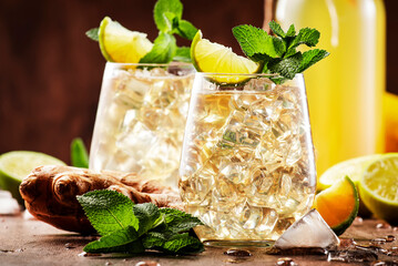 Classic Ginger Ale Cocktails with Beer, Lime, Lemon and Mint Leaves in glaasses on wooden table, negative space